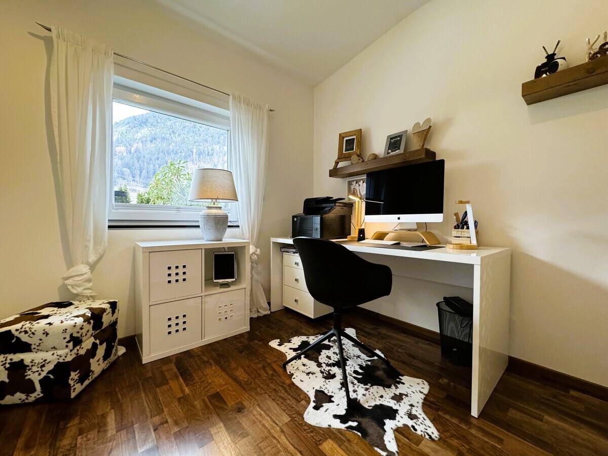 Arbeitszimmer mit Schreibtisch, Fenster und Blick auf die grüne Umgebung.