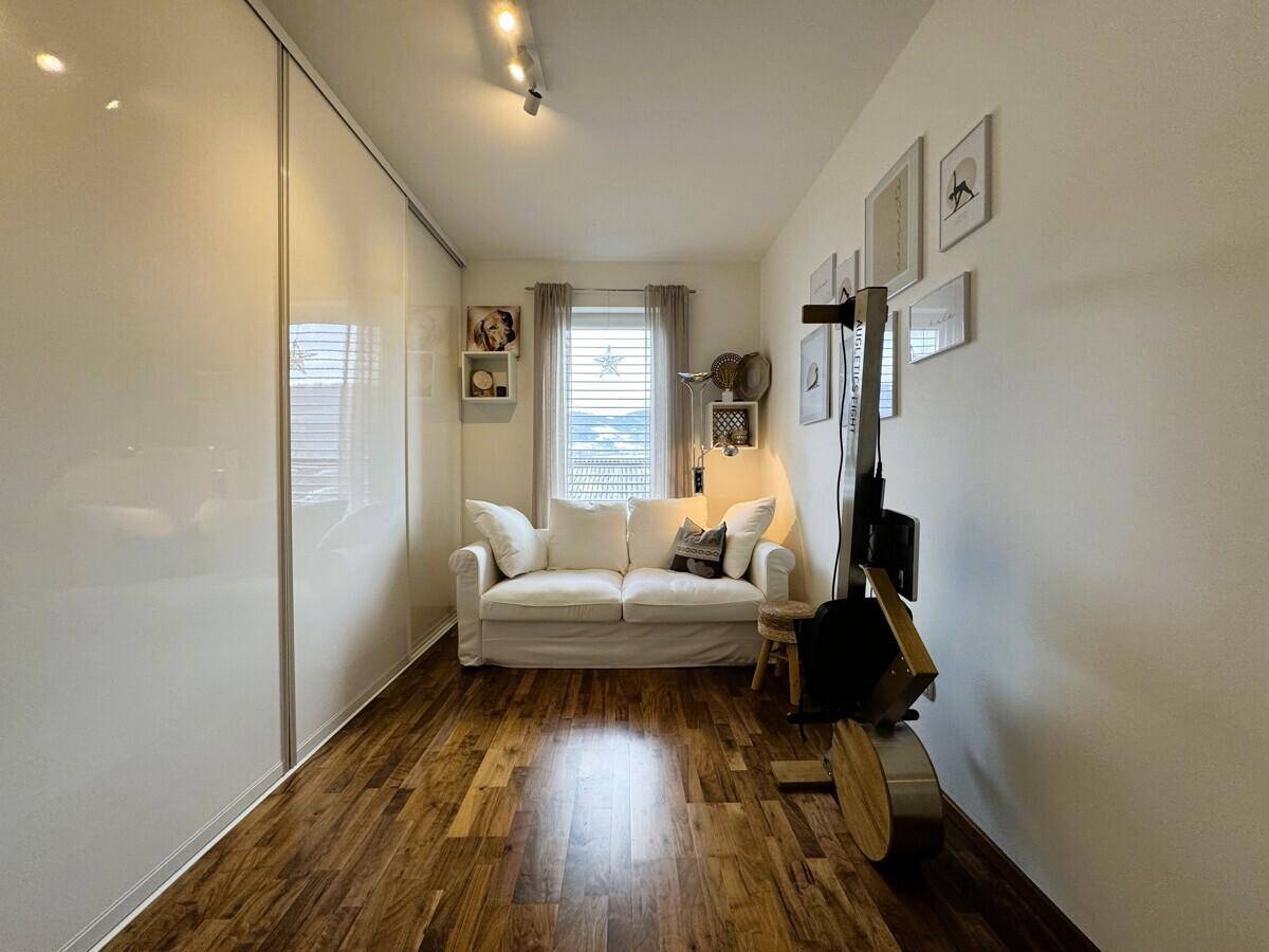 Helles Zimmer mit Sofa, großem Kleiderschrank und Holzboden.