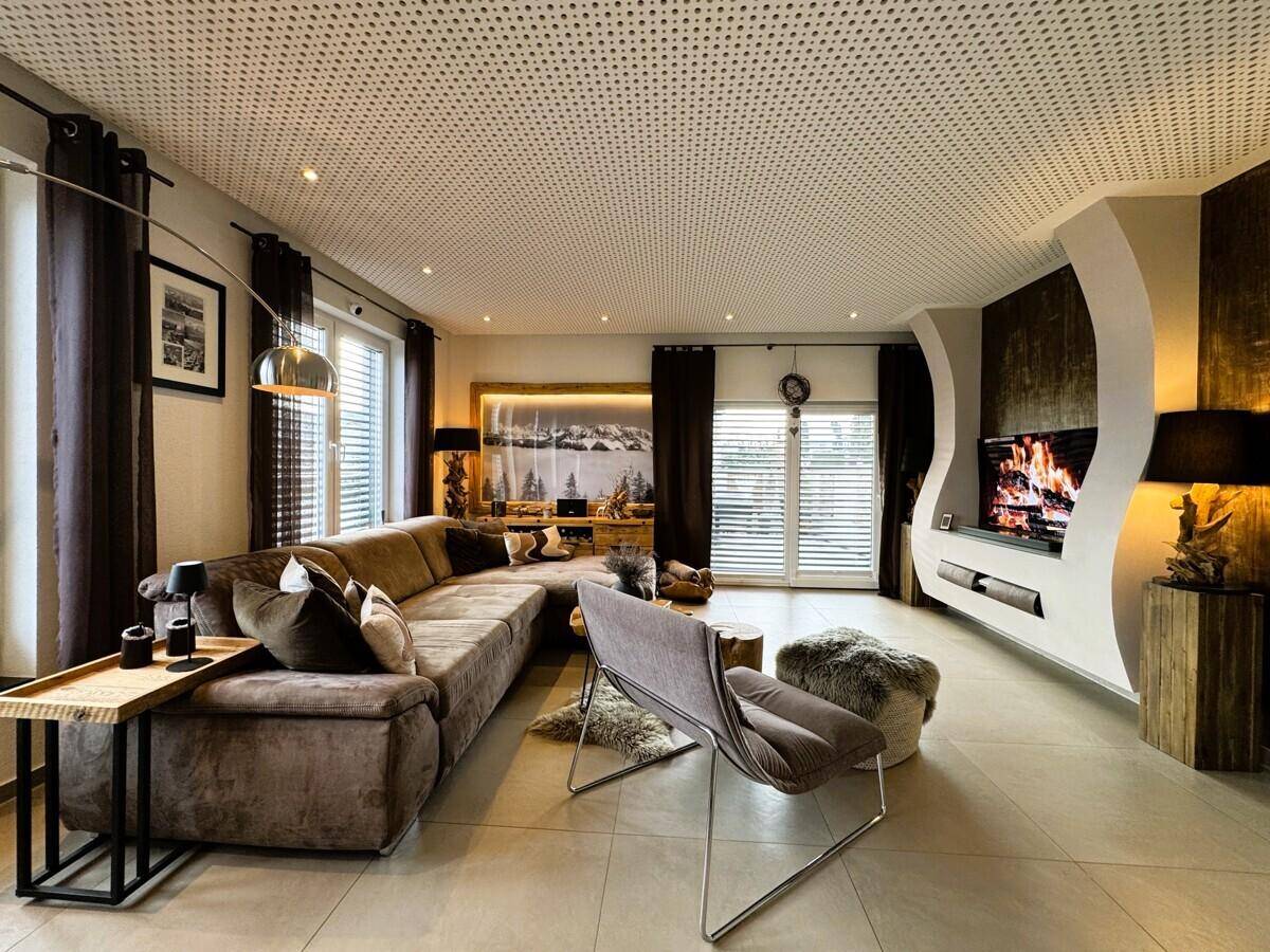 Geräumiges Wohnzimmer mit großem Ecksofa, Kamin und modernen Holzakzenten.