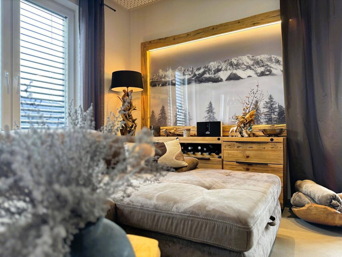 Gemütlicher Wohnbereich mit großem Sofa, Holzelementen und indirekter Beleuchtung.