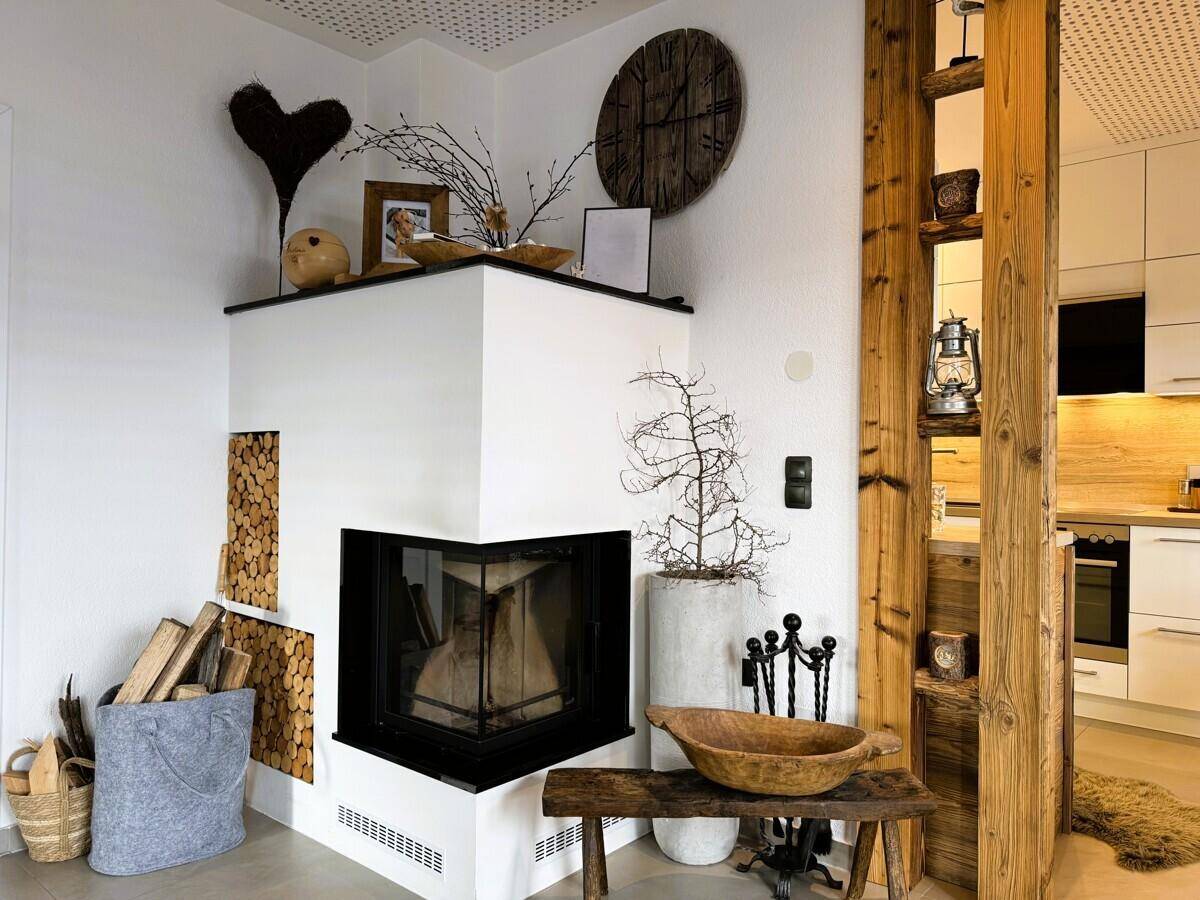 Moderner Kamin mit Holzablage und rustikalen Dekorationselementen im Wohnzimmer.