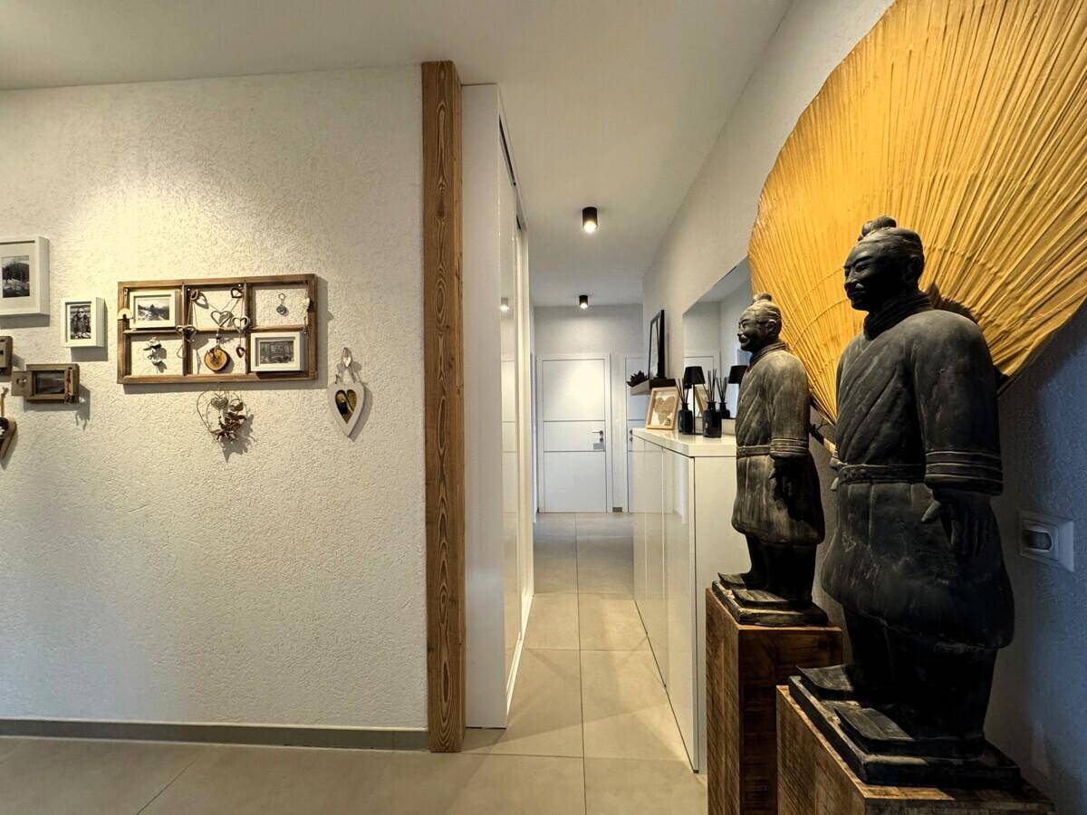 Heller Flur mit Holzelementen und dekorativen Statuen.