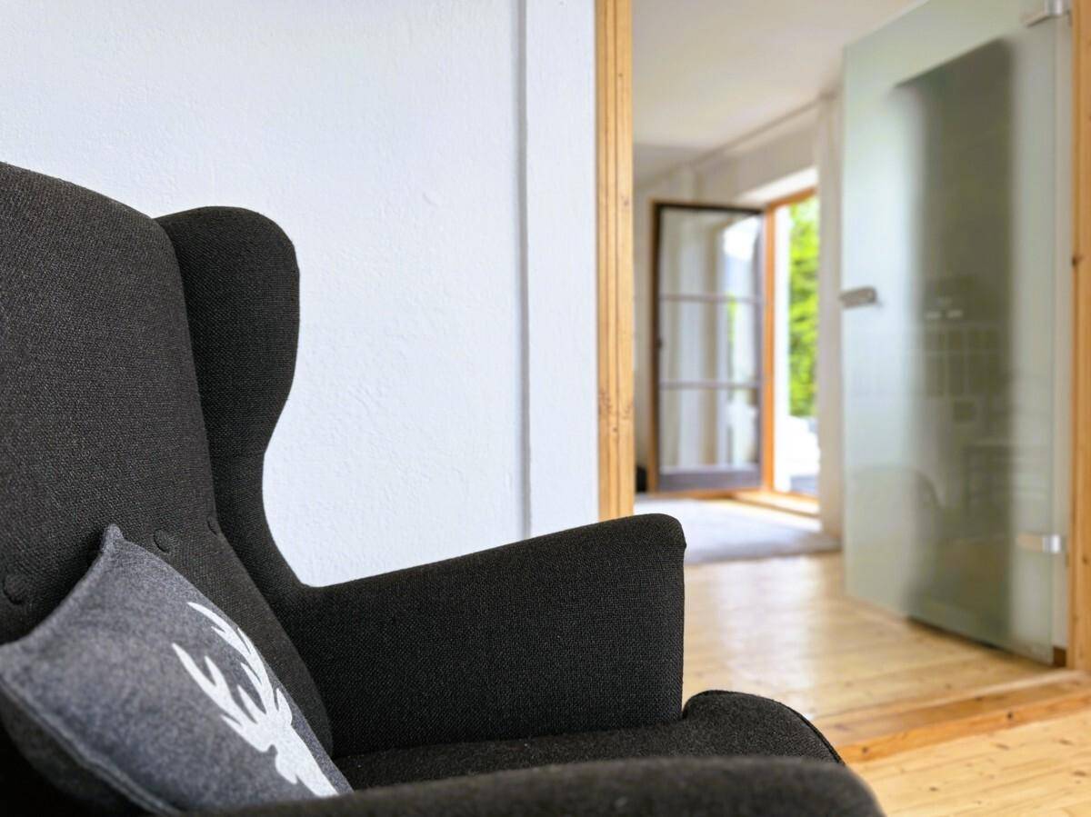 Gemütlicher Sessel im Wohnzimmer mit Blick auf eine Milchglastür und Holzboden.