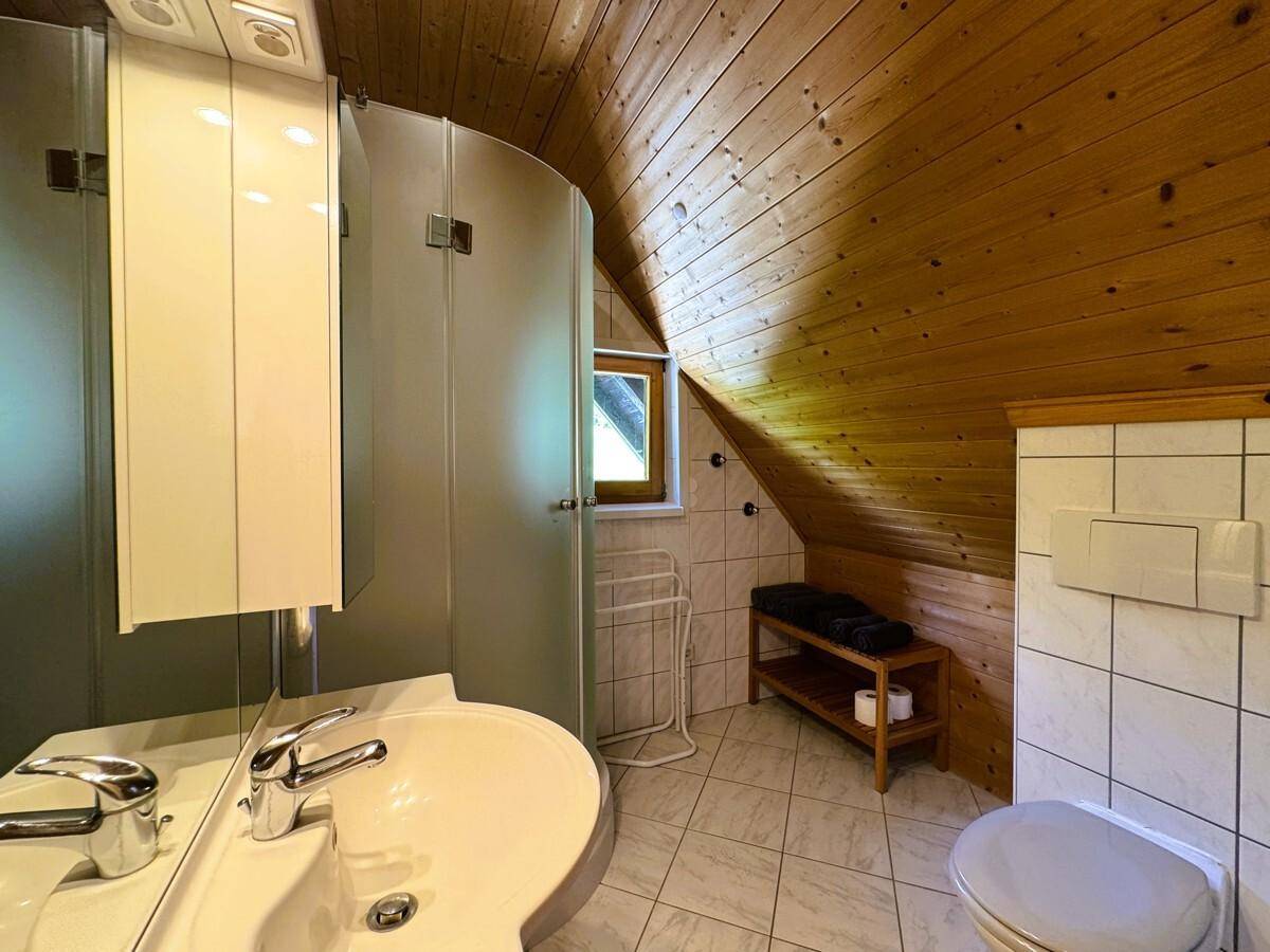Badezimmer im Dachgeschoss mit Dusche, WC und Holzverkleidung an der Decke.
