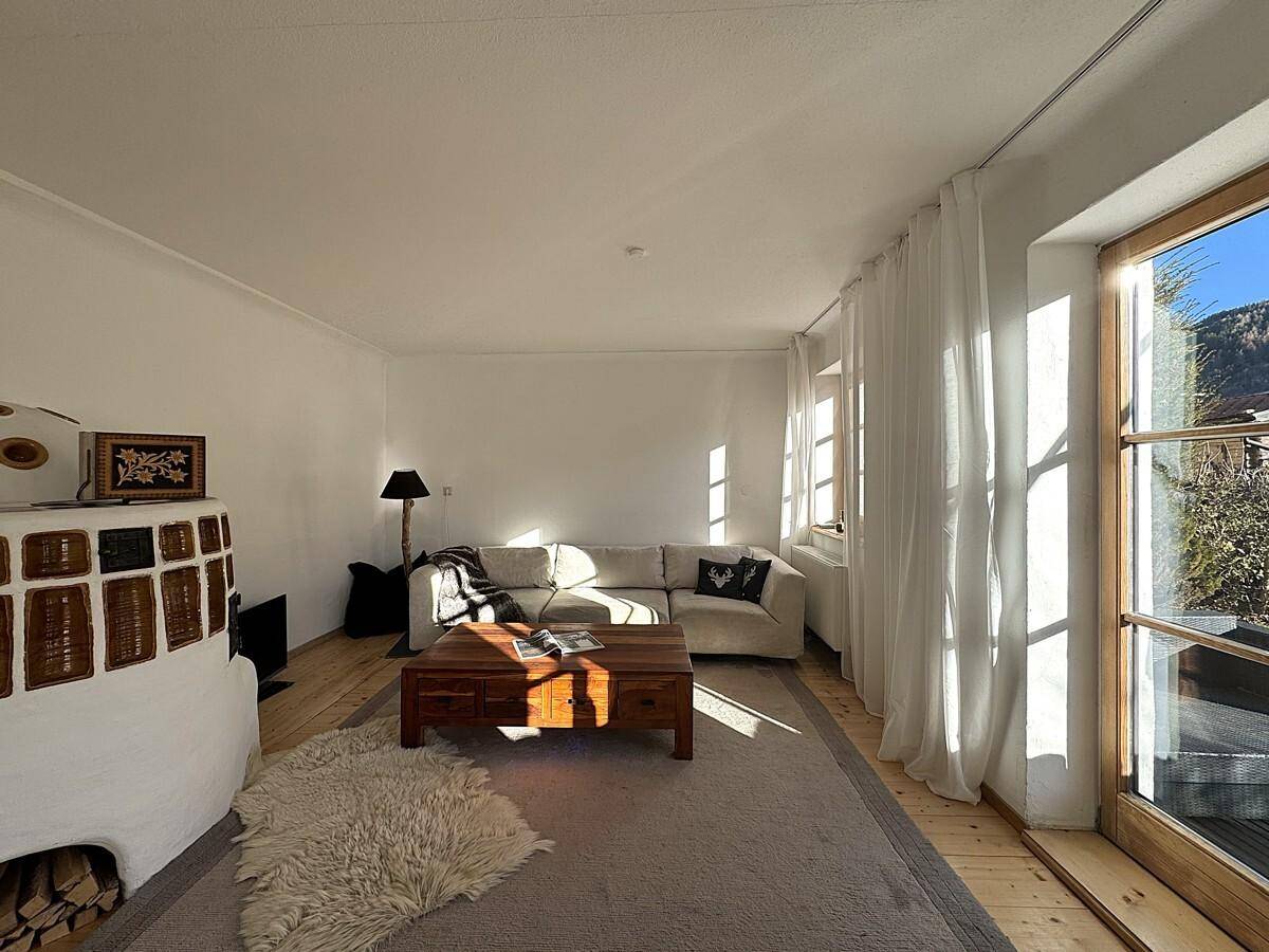 Sonniges Wohnzimmer mit beigem Sofa, Holztisch und viel Tageslicht.