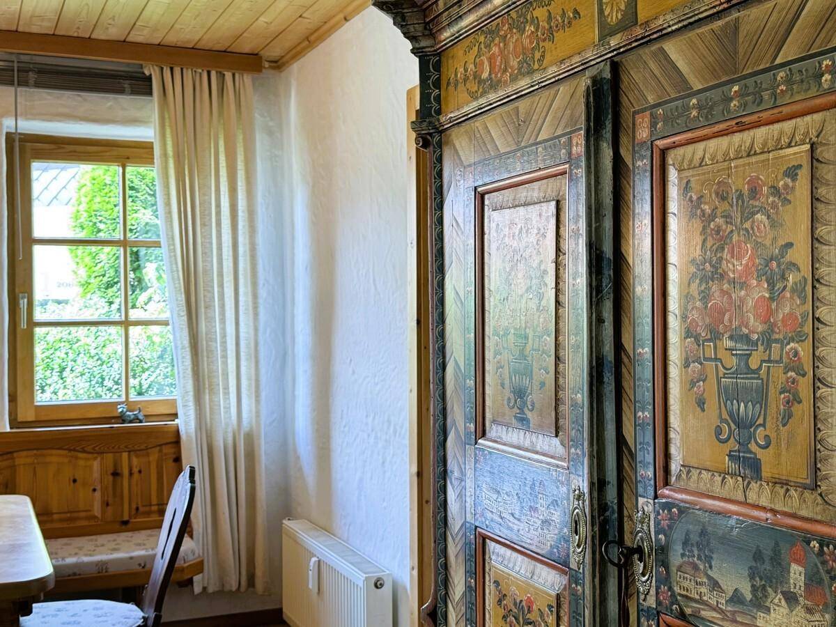 Nahaufnahme eines kunstvoll bemalten Schranks neben einem Fenster im Esszimmer.
