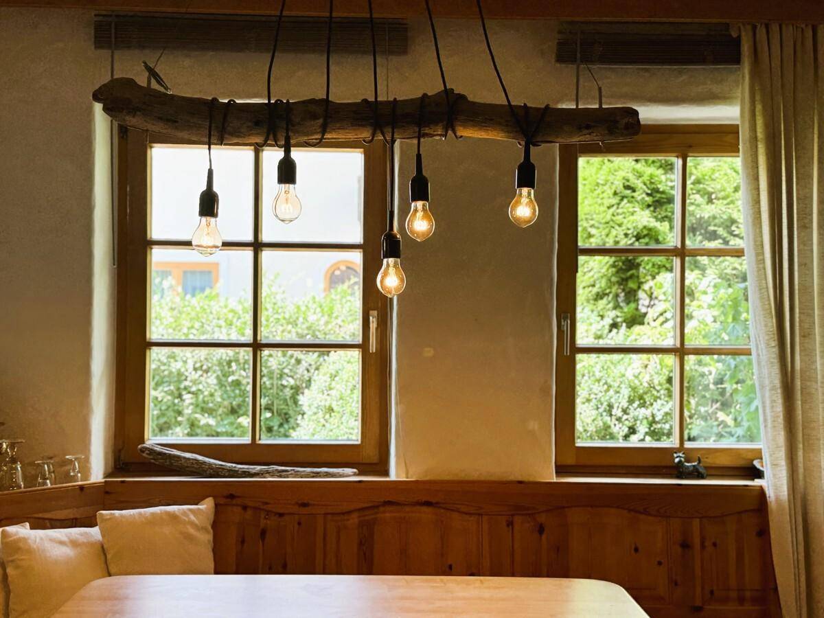 Detailansicht des Fensters im Essbereich mit Holzbalken-Lampe und Blick ins Grüne.