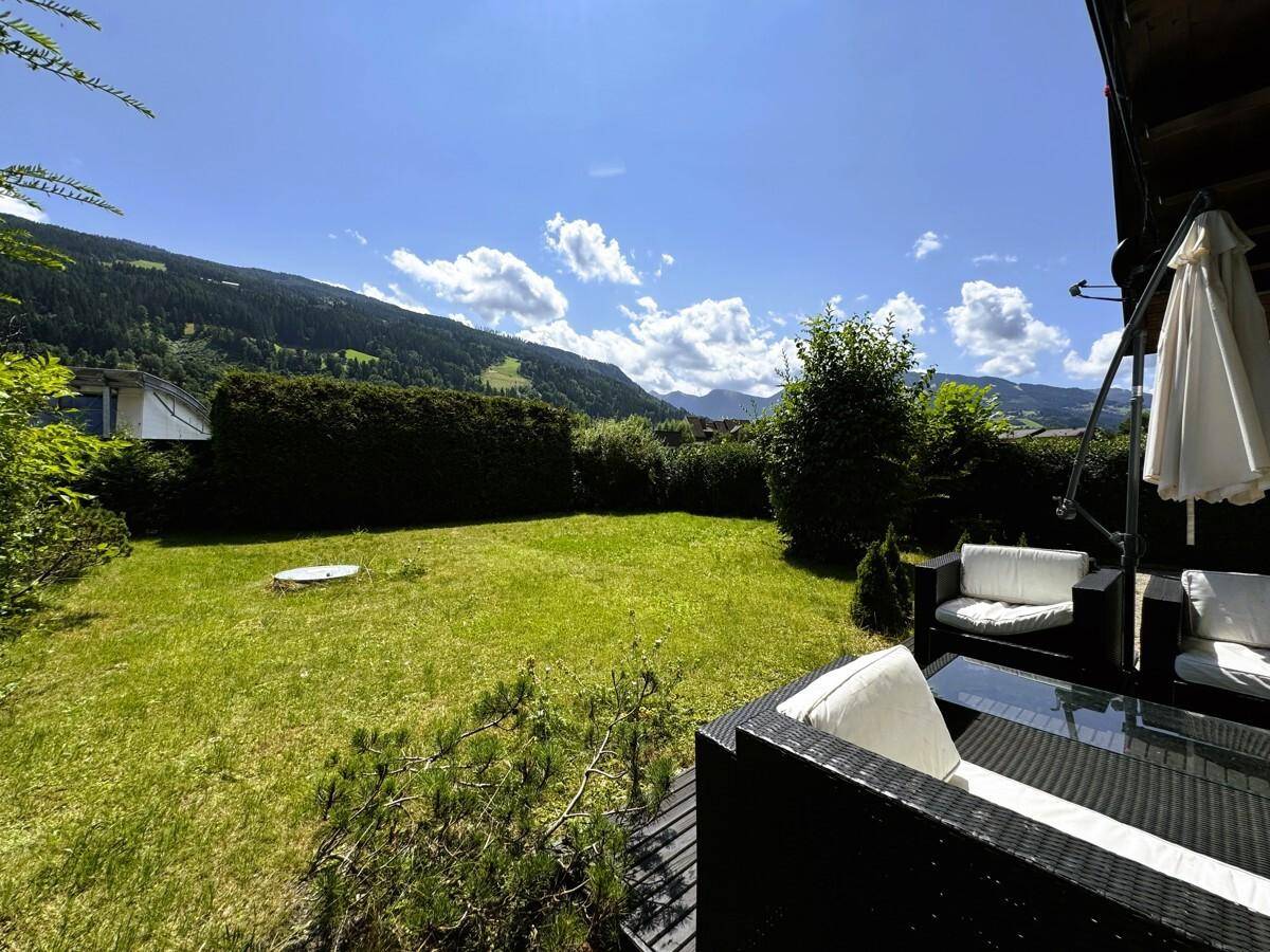 Gepflegter Garten mit Terrasse, Sitzgelegenheiten und weitem Bergblick.