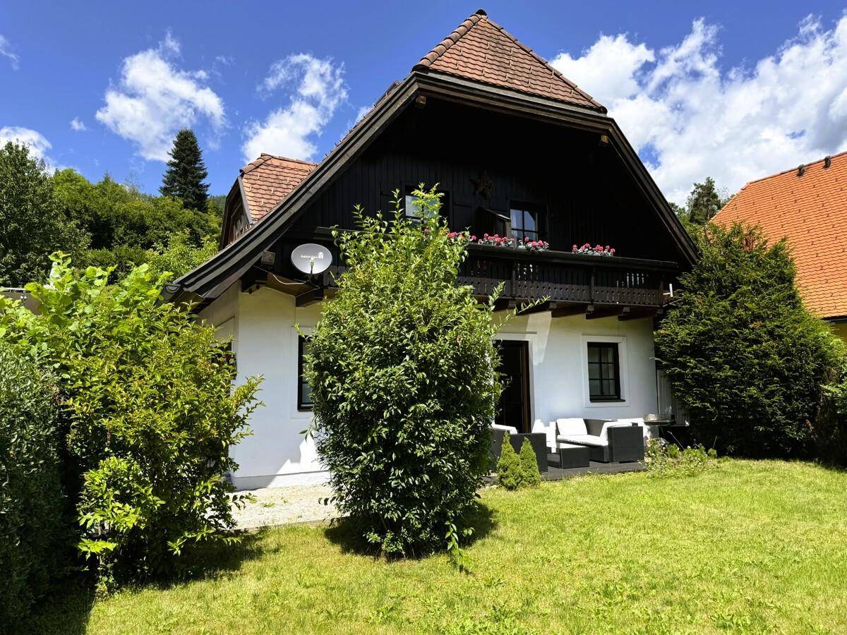 Vorderansicht des traditionellen Hauses mit gepflegtem Garten und Holzbalkon.