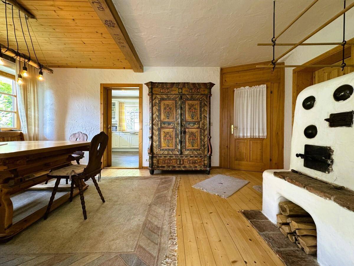 Geräumiger Essbereich mit Kachelofen, bemaltem Schrank und Zugang zur Küche.