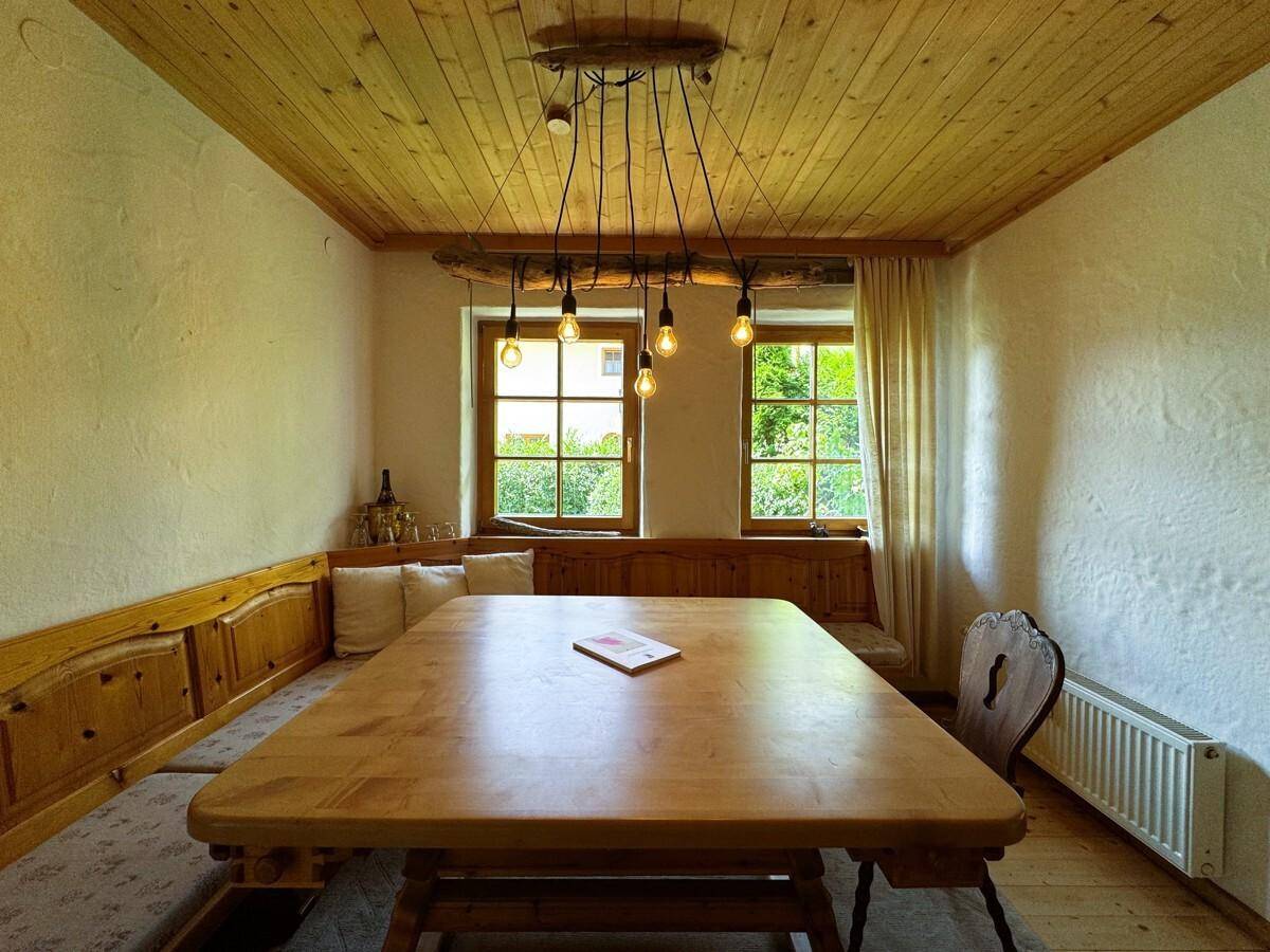 Rustikaler Essbereich mit Holztisch, Eckbank und Deckenverkleidung aus Holz.
