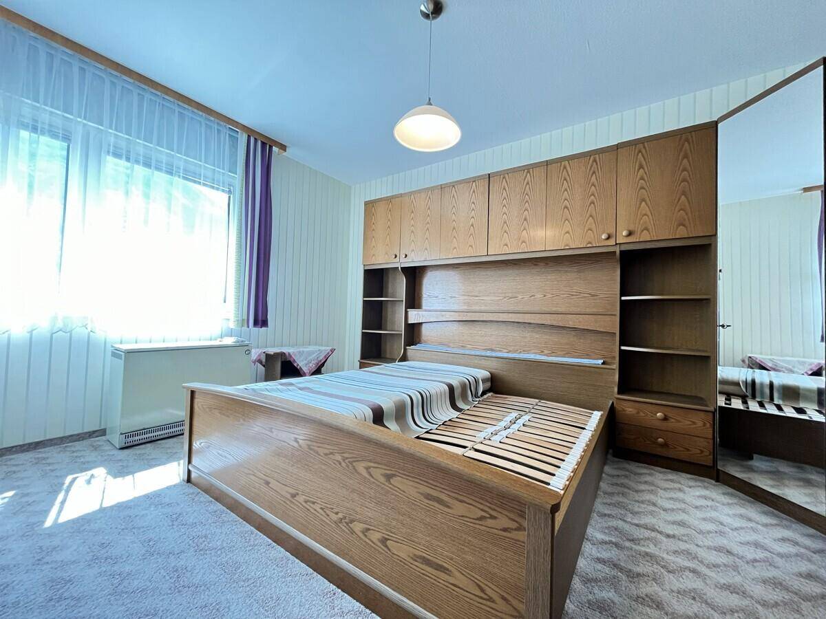 Schlafzimmer mit Holzbett und integrierten Schränken, großem Spiegel und Teppichboden.