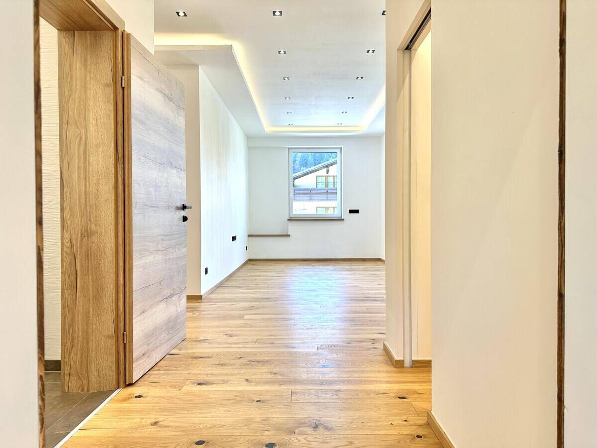 Heller Flur mit Holzboden, indirekter Beleuchtung und Blick nach draußen.