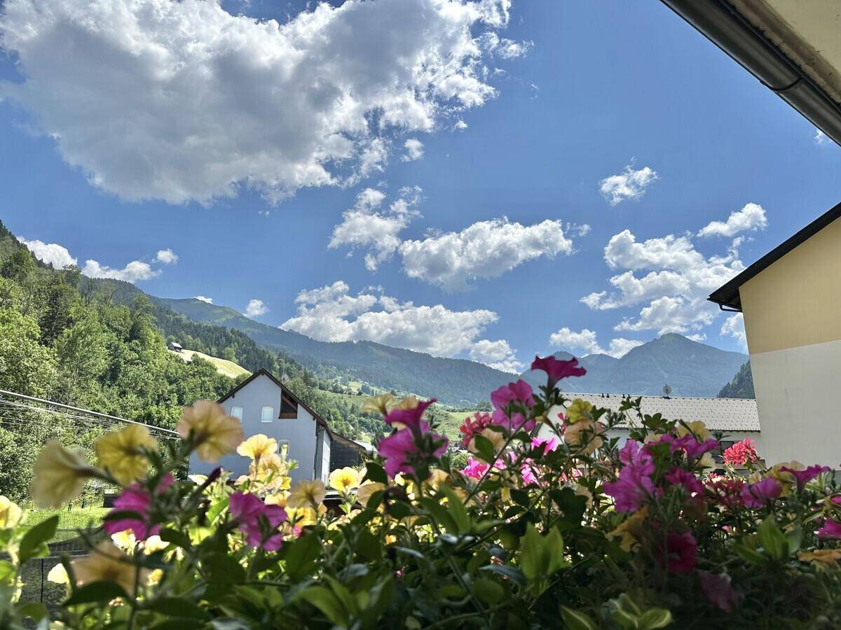 Balkon mit bunten Blumenkästen und weitem Blick auf die umliegende Berglandschaft.
