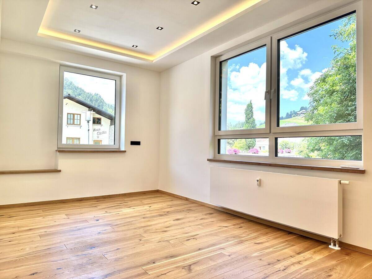 Heller Wohnraum mit Holzboden, großen Fenstern und Blick auf die Umgebung.