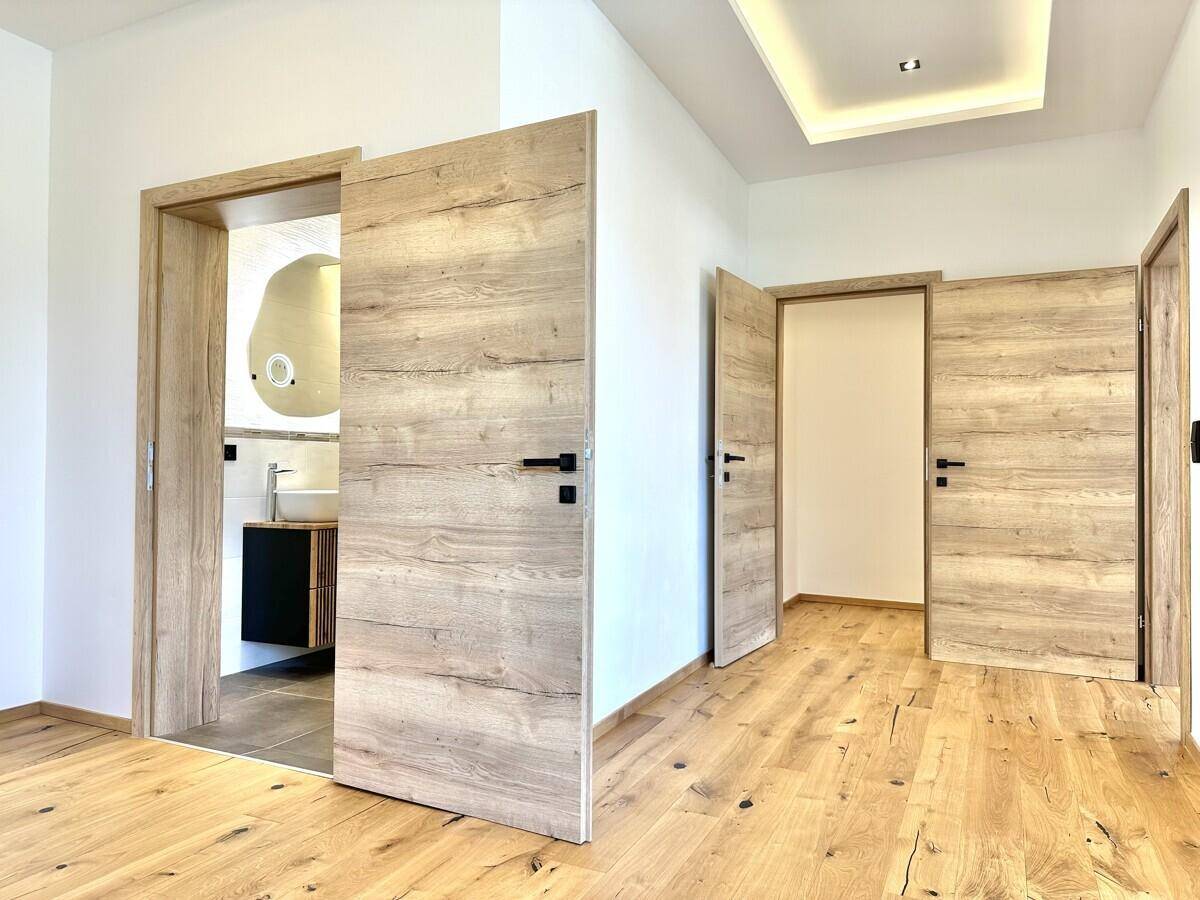 Flur mit Holzboden und mehreren Holztüren, die zu verschiedenen Räumen führen.