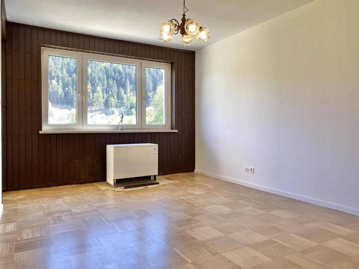 Geräumiges Zimmer mit dunkler Holzverkleidung, großem Fenster und Bergblick.