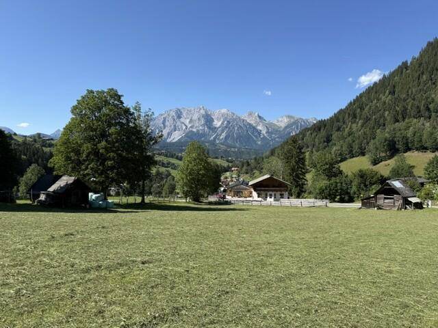Ländliche Szenerie mit traditionellen Gebäuden und weitem Blick auf die Berge.