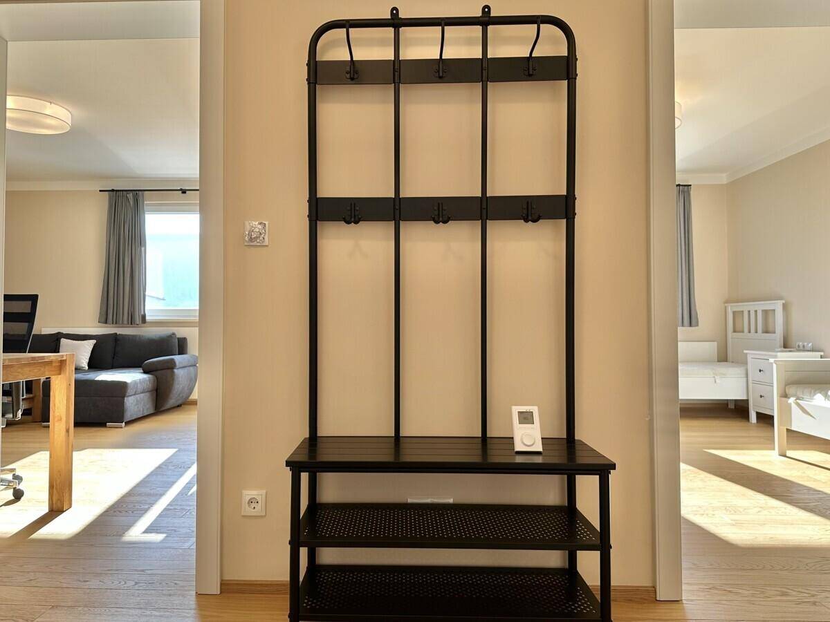 Heller Eingangsbereich mit Garderobe und offenem Zugang zu Wohn- und Schlafzimmer.
