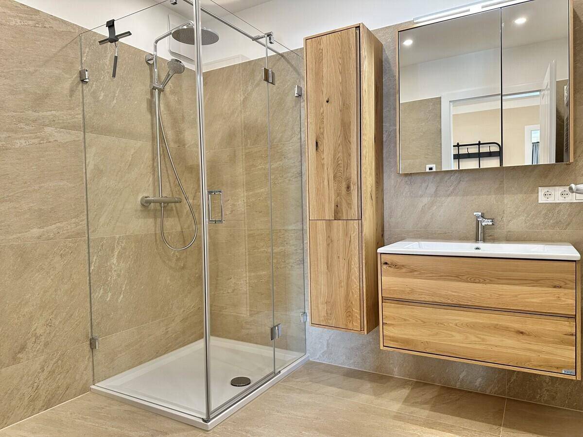 Modernes Badezimmer mit begehbarer Dusche, schwebendem Holzwaschtisch und Spiegelschrank.