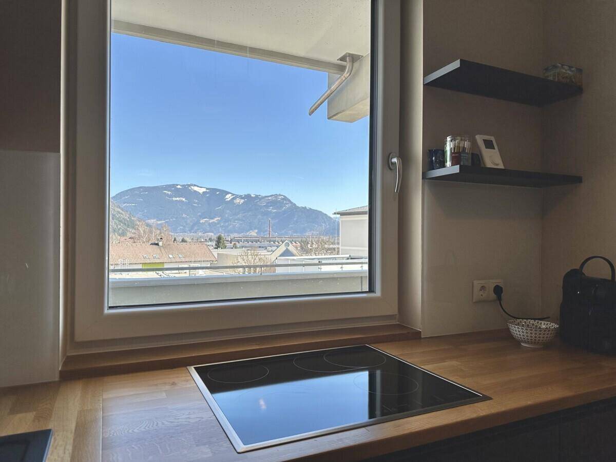 Küchenzeile mit Induktionskochfeld, Holzarbeitsplatte und Fenster mit weitem Bergblick.
