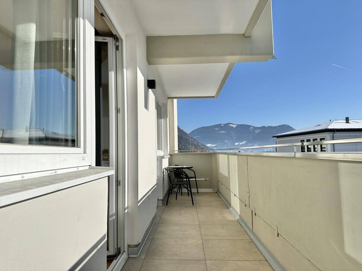 Balkon mit kleiner Sitzecke und Panoramablick auf die Berge.