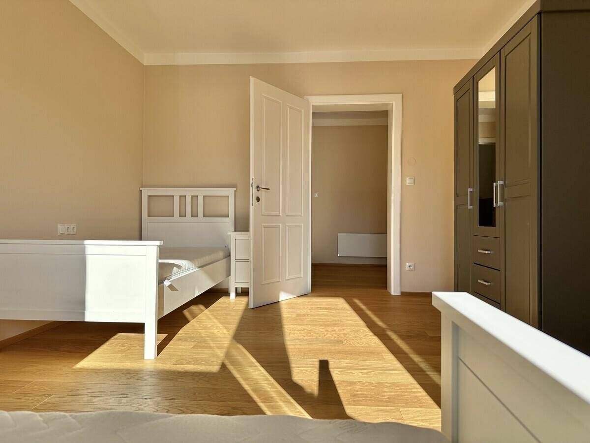 Helles Schlafzimmer mit zwei Einzelbetten, Kleiderschrank und Holzboden.