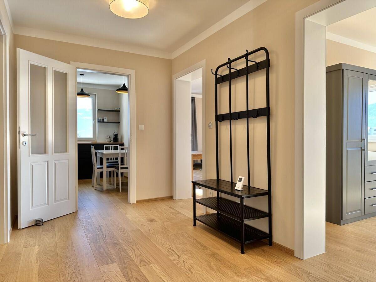 Geräumiger Flur mit Holzboden, Garderobe und Zugang zu Küche und Schlafzimmer.