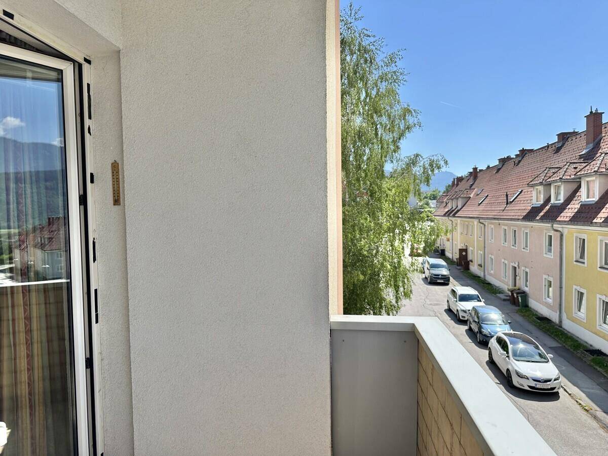 Kleiner Balkon mit Blick auf die ruhige Wohnstraße und umliegende Häuser.