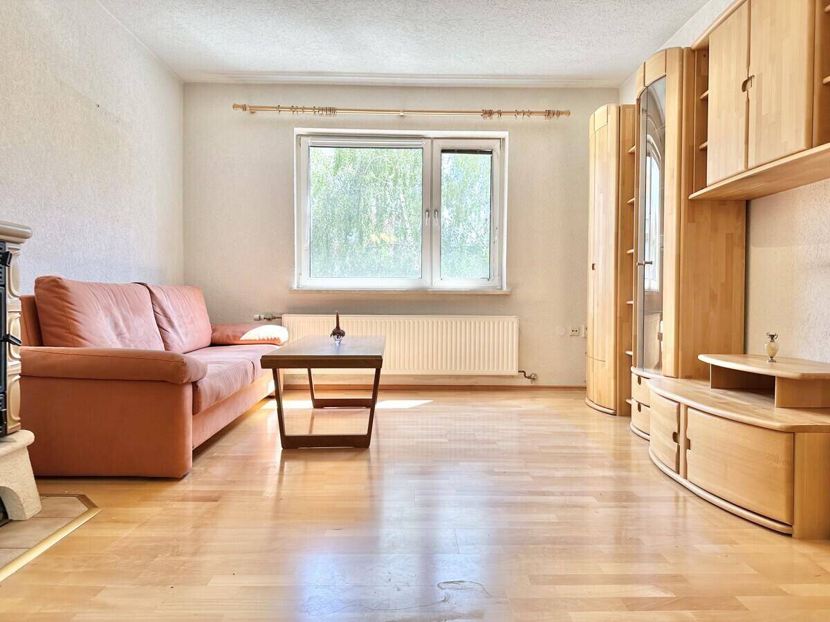 Wohnzimmer mit Parkettboden, Sofa und Holzmöbeln, bereit zur individuellen Gestaltung.