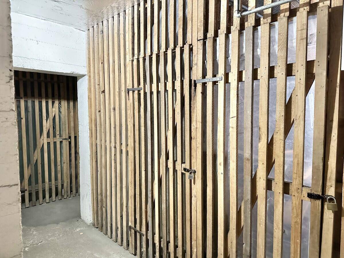 Kellerabteile mit Holzlattenwänden, bieten zusätzlichen Stauraum für Bewohner.