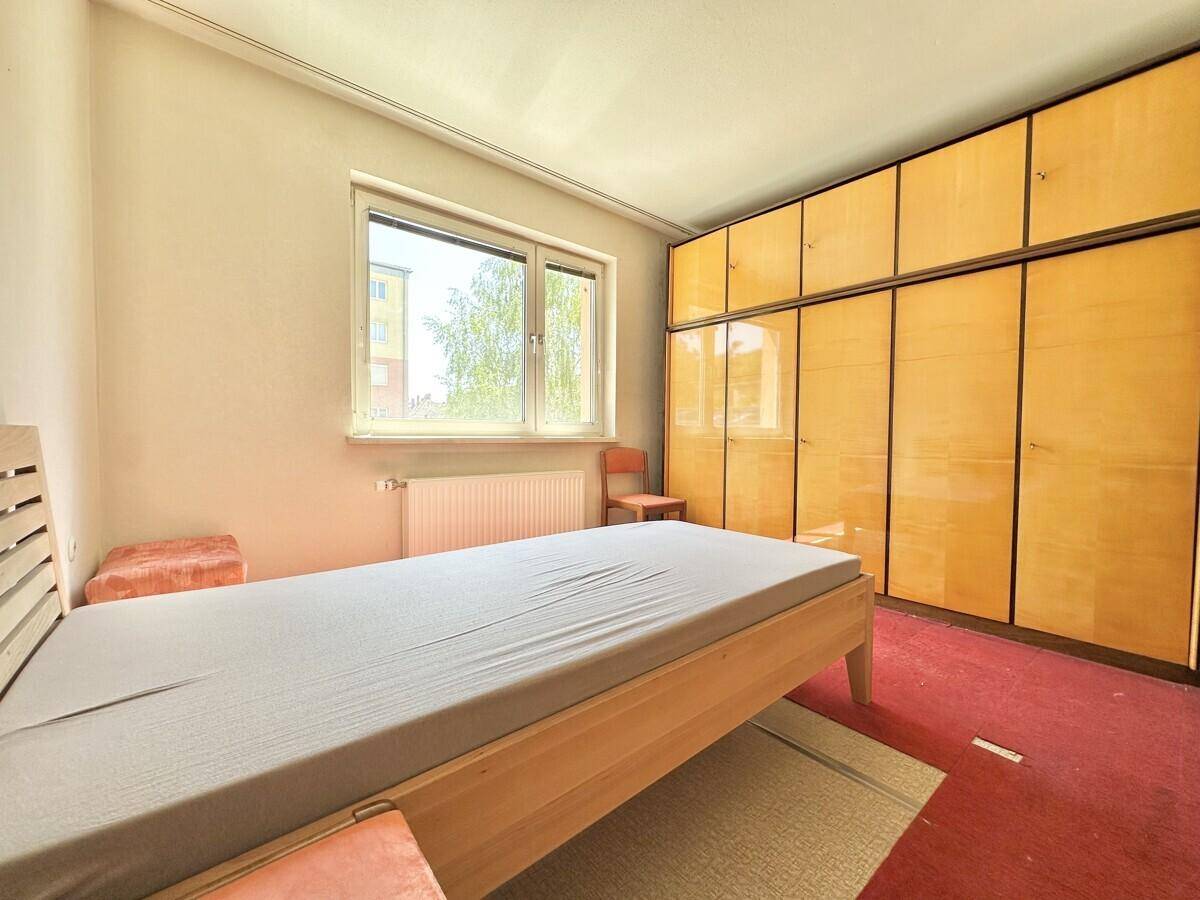 Schlafzimmer mit Einzelbett, Teppichboden und großem Kleiderschrank.