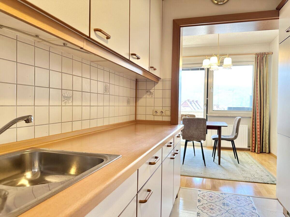 Funktionale Küche mit Holz-Arbeitsplatte und Blick in den Essbereich.