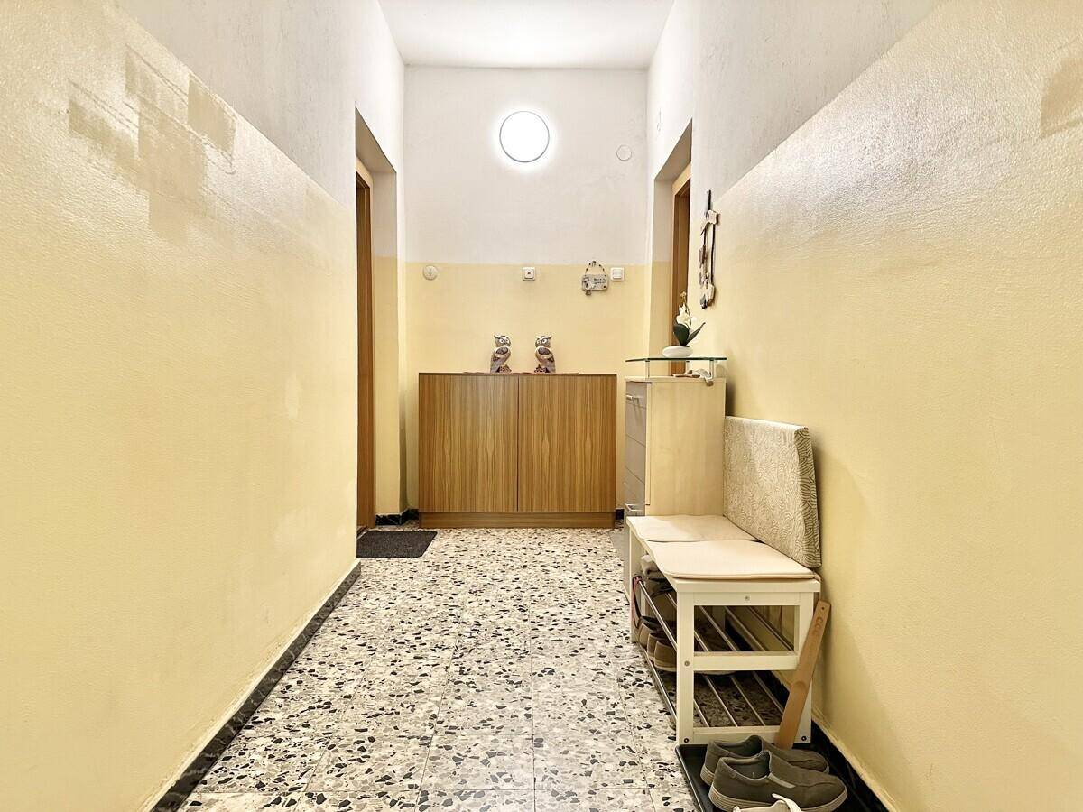 Heller Flur mit Terrazzoboden, Garderobe und gelb gestrichenen Wänden.
