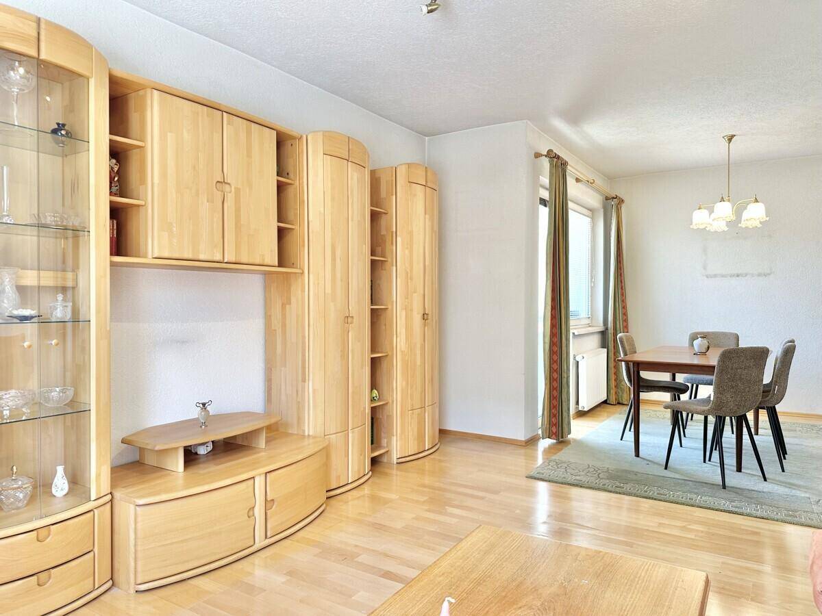 Geräumiger Wohn-Essbereich mit Holzmöbeln, Parkettboden und viel Tageslicht.