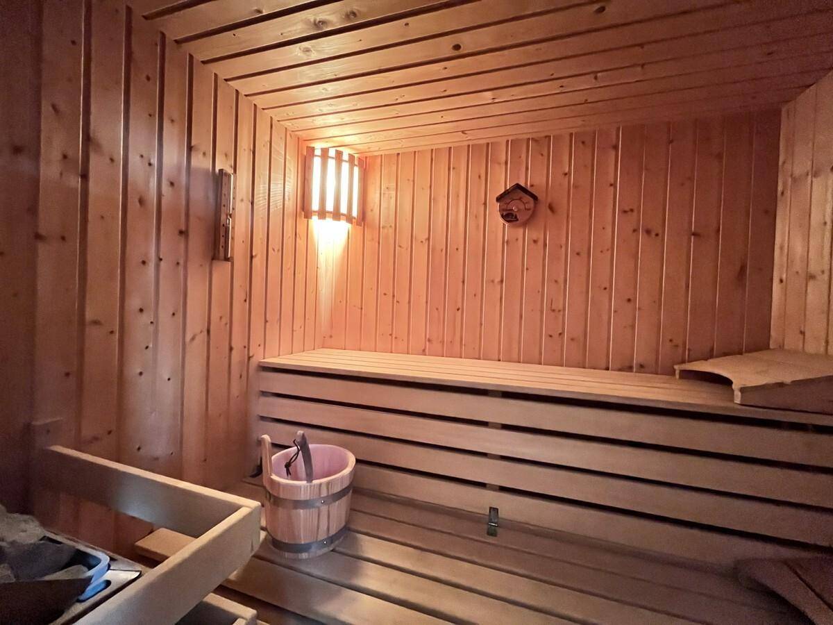 Holzvertäfelte Sauna mit Bänken und traditionellem Aufgusseimer für entspannende Momente.