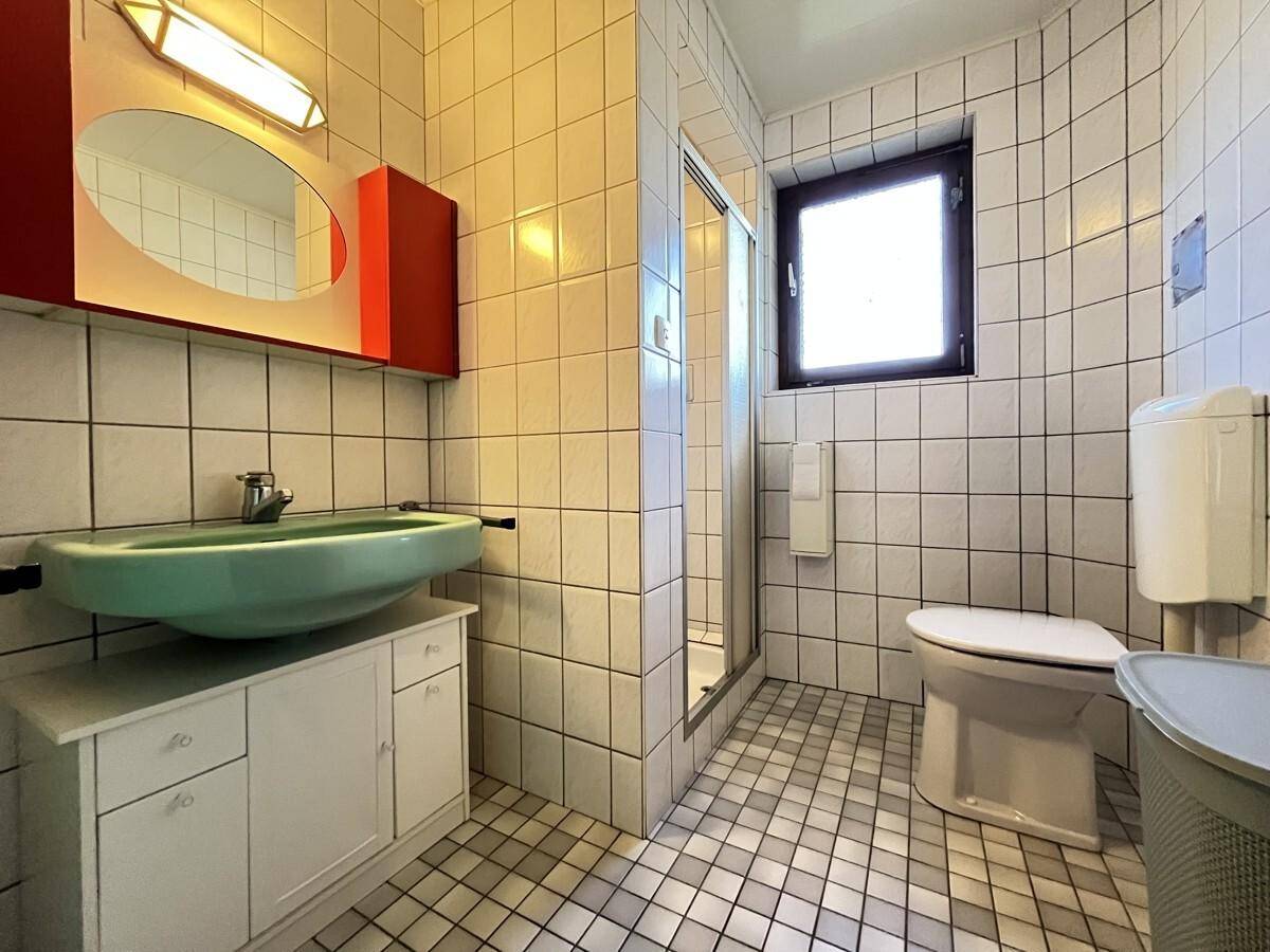Badezimmer mit mintgrünem Waschbecken, weißen Fliesen und Duschkabine.