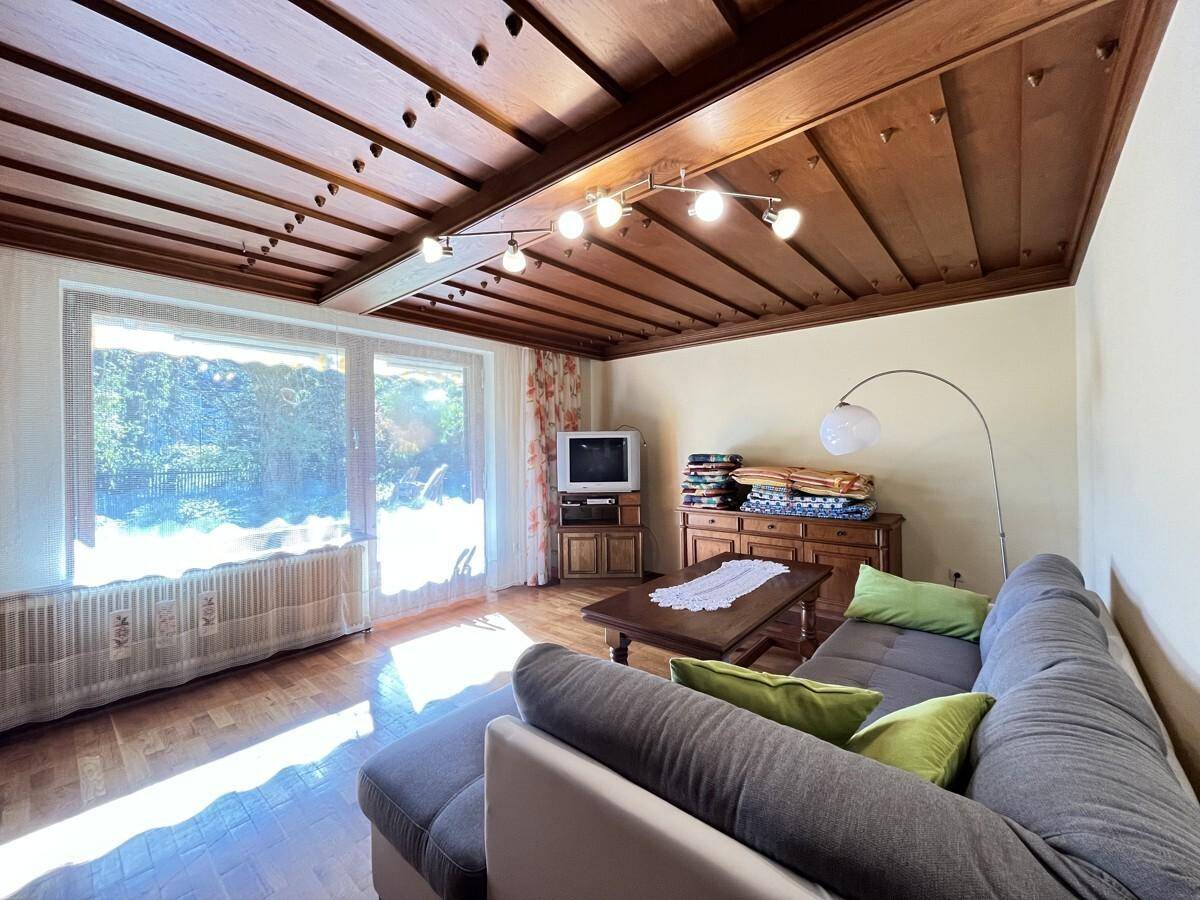Helles Wohnzimmer mit Holzbalkendecke, Parkettboden und gemütlicher Sitzecke.