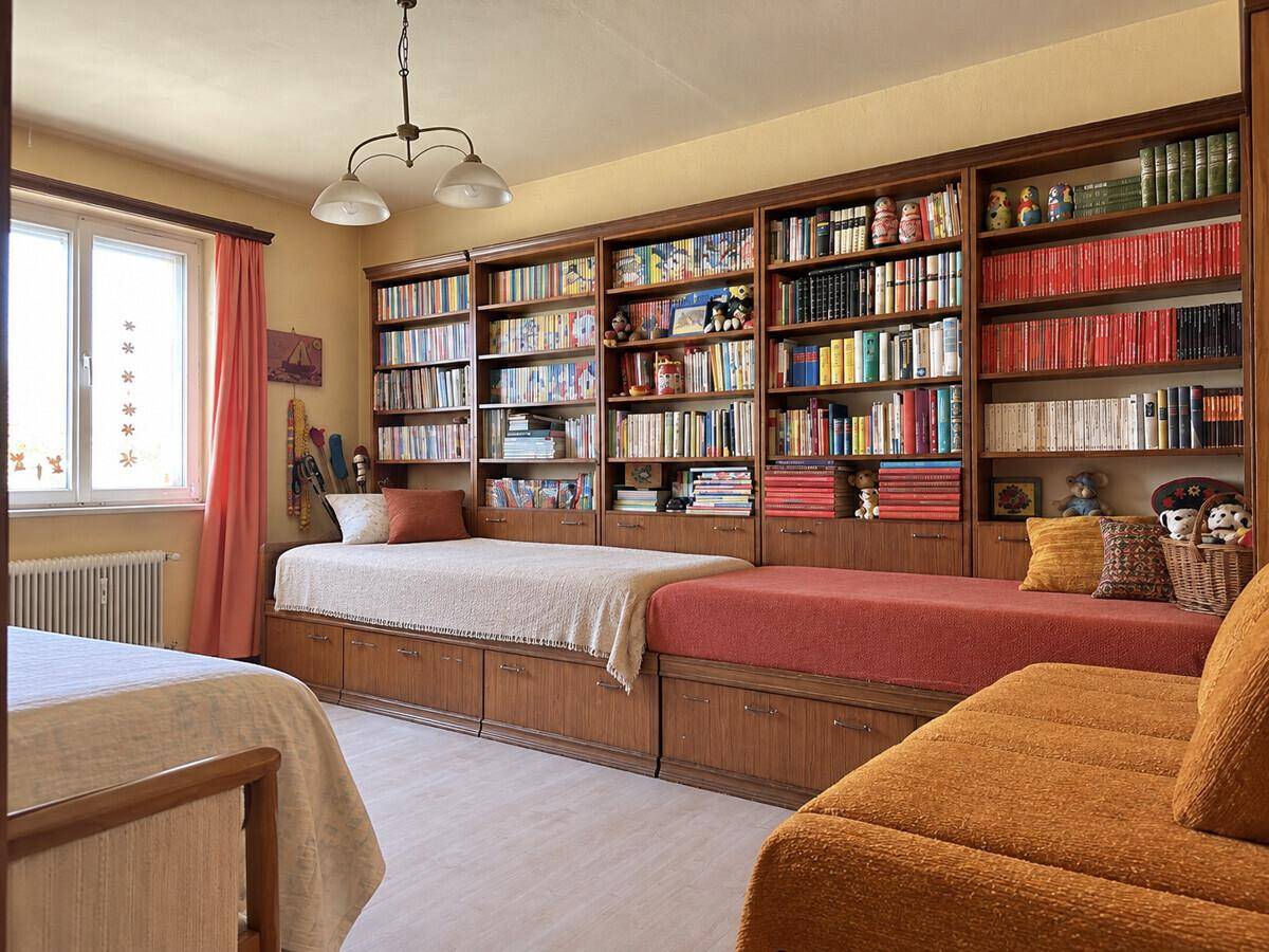 Schlafzimmer mit zwei Betten, großen Bücherregalen und einem Fenster für natürliches Licht.