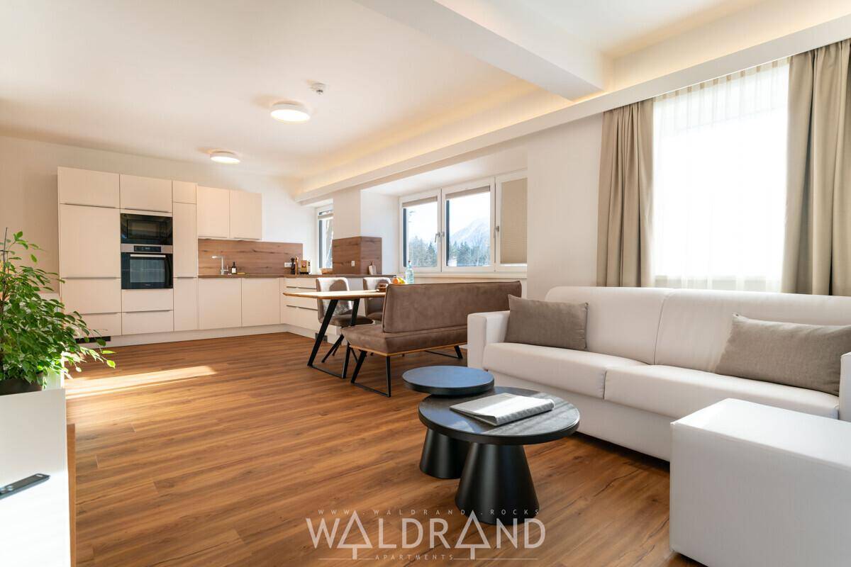 Offener Wohn- und Essbereich mit moderner Küche, Sofa und Holzboden.