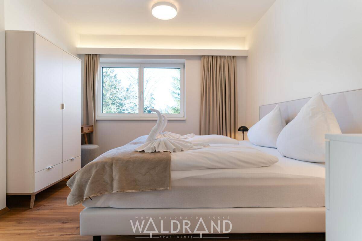 Gemütliches Schlafzimmer mit Doppelbett, Fenster und hellem Kleiderschrank.