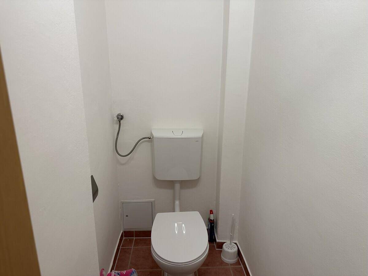 Separate Gästetoilette mit WC und Fliesenboden, in schlichtem Design gehalten.
