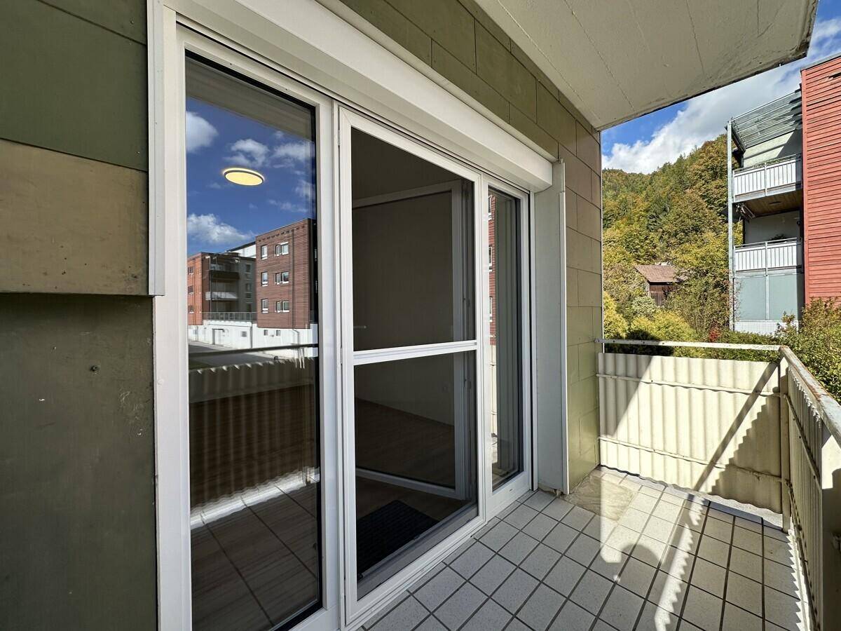 Balkon mit Fliesenboden und Blick auf die Umgebung, ausgestattet mit Rollladen.