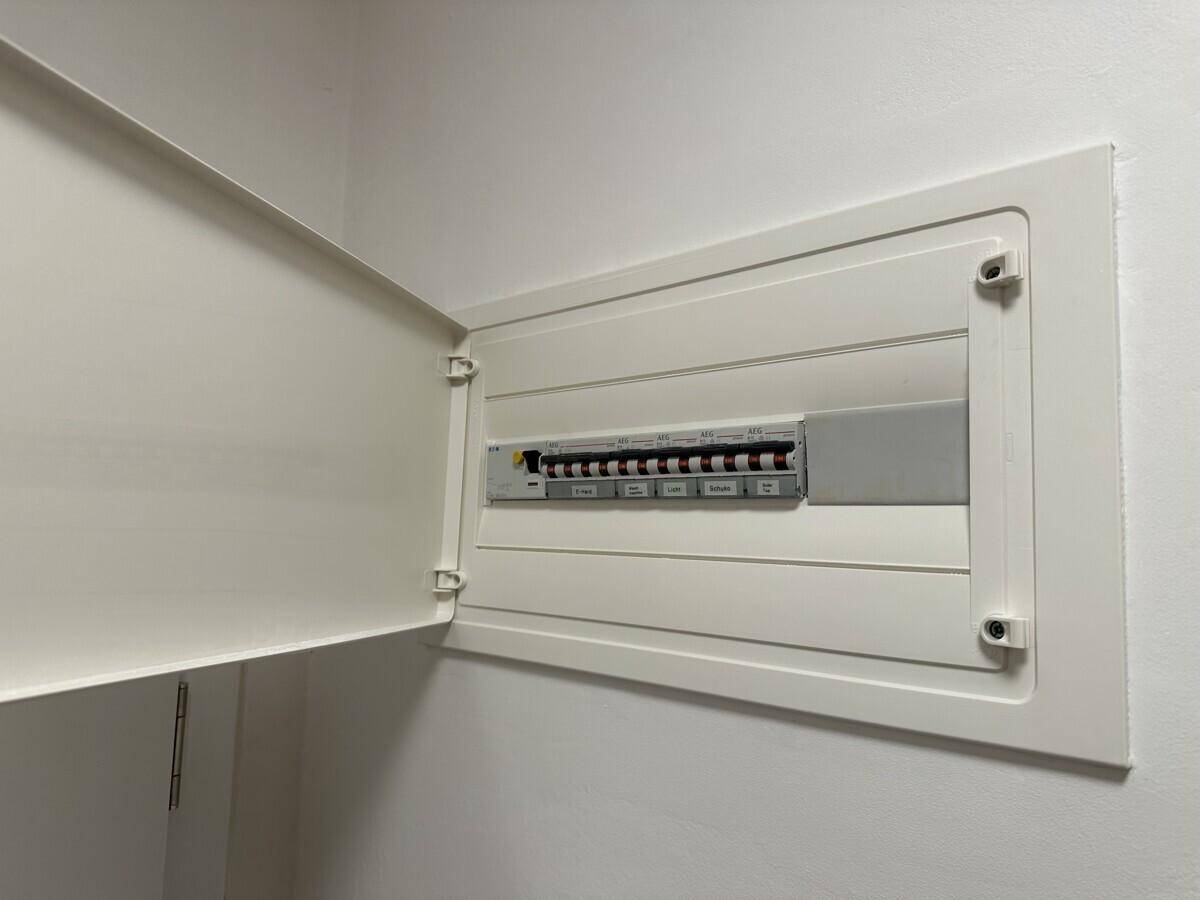 Offener Sicherungskasten mit mehreren Schaltern, ordentlich in der Wand verbaut.