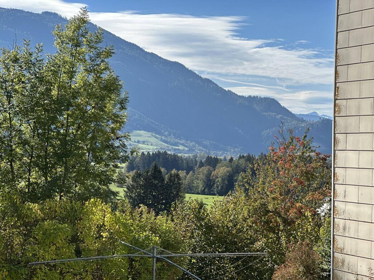 Panoramablick auf die umliegende Berglandschaft und grüne Täler an einem sonnigen Tag.