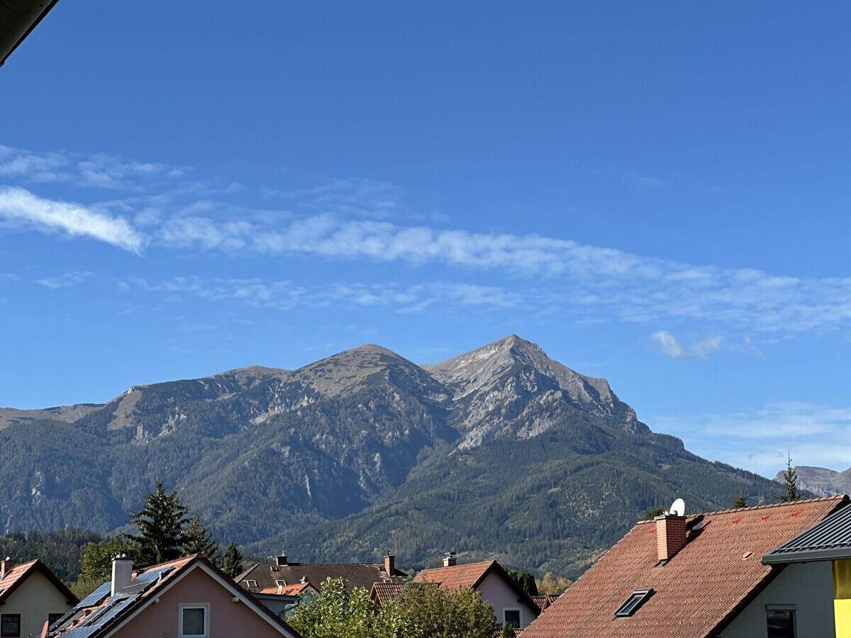 Panoramablick auf majestätische Berge über den Dächern einer Wohnsiedlung.