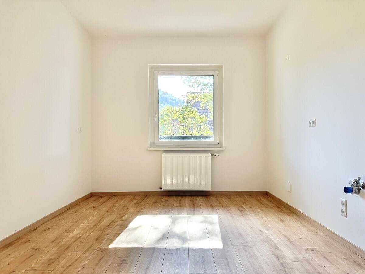 Heller Raum mit Holzboden und Anschlüssen für eine zukünftige Küche.