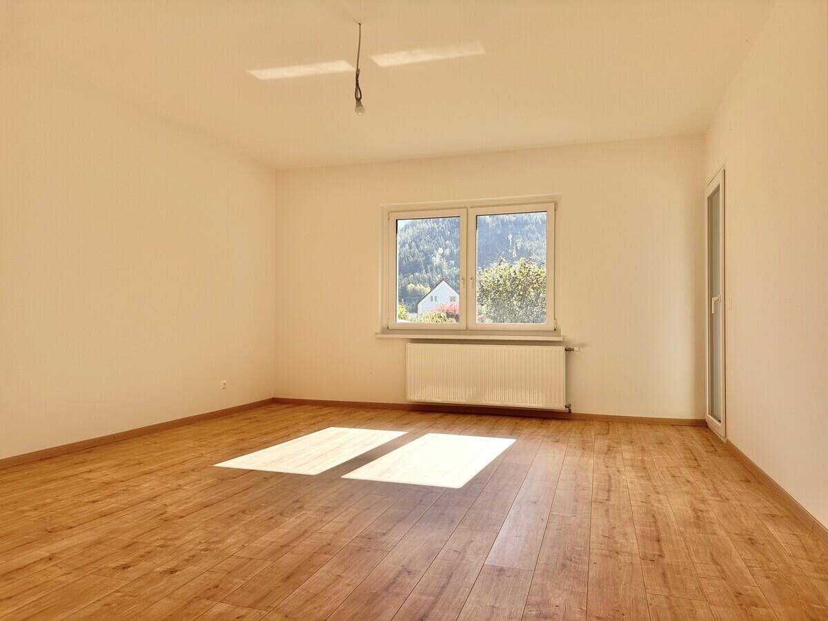 Lichtdurchflutetes Zimmer mit Holzboden und Ausblick auf die umliegende Natur.