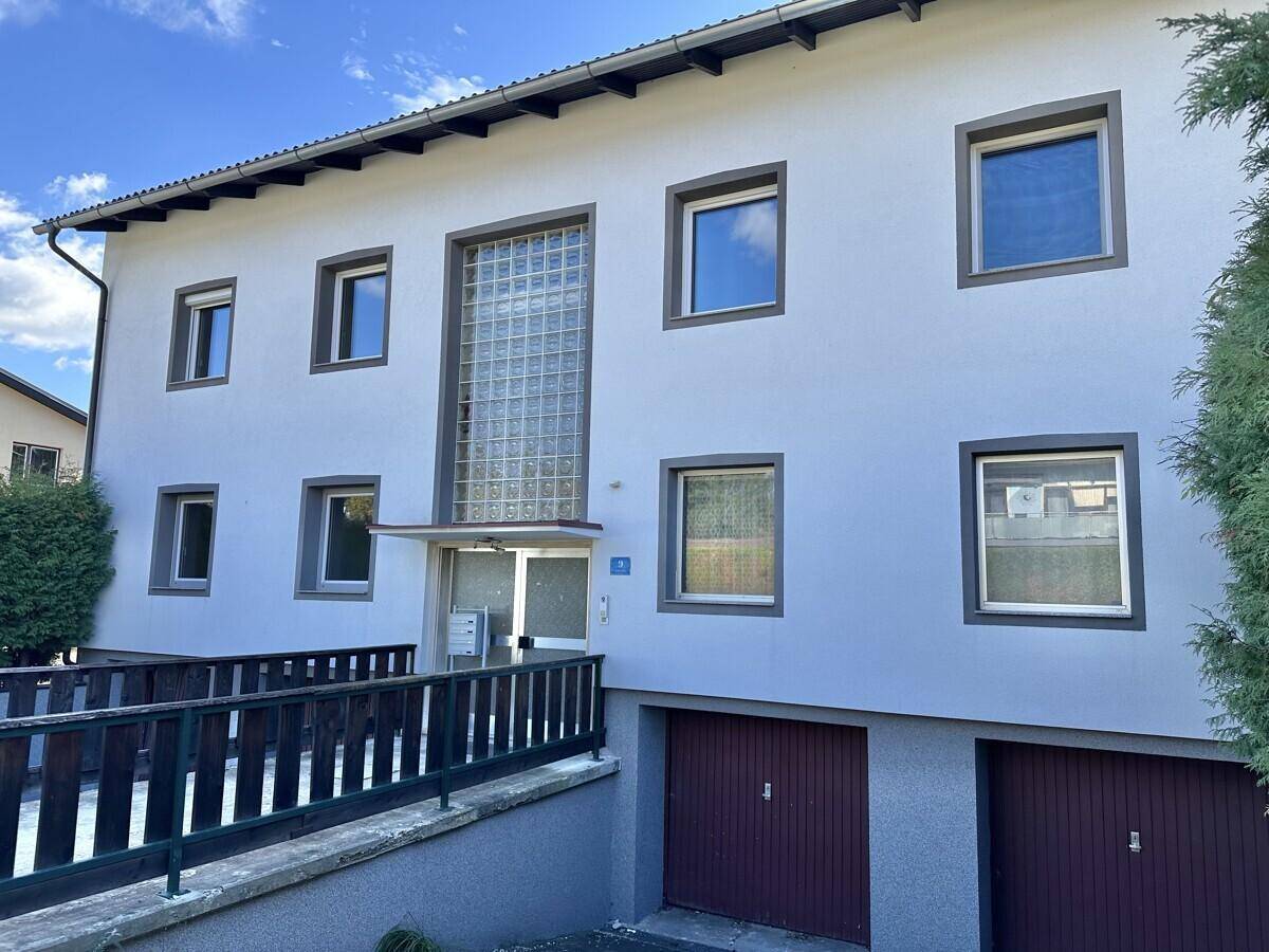 Vorderansicht eines Mehrfamilienhauses mit Garagen und Eingangsbereich.
