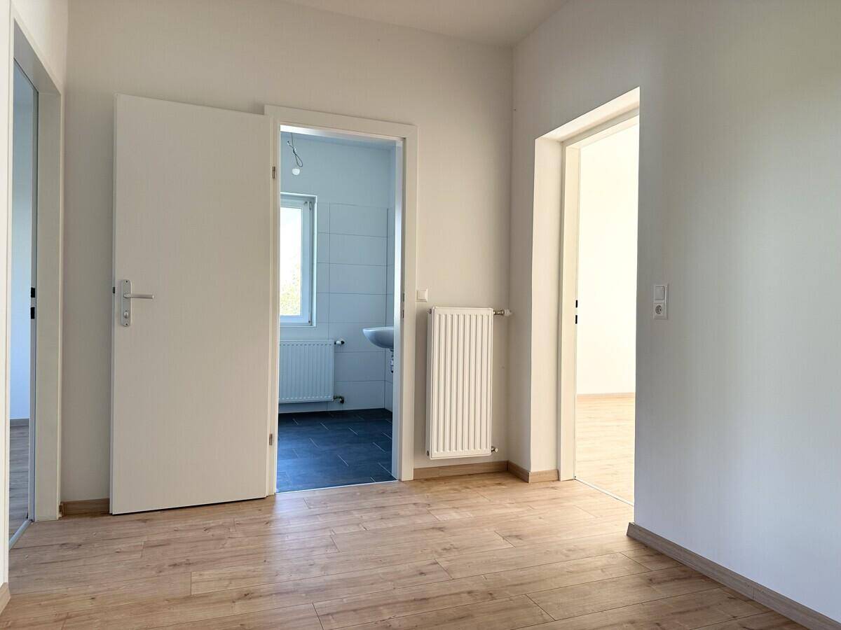 Heller Flur mit Holzboden und Türen zu angrenzenden Räumen, inklusive Badezimmer.